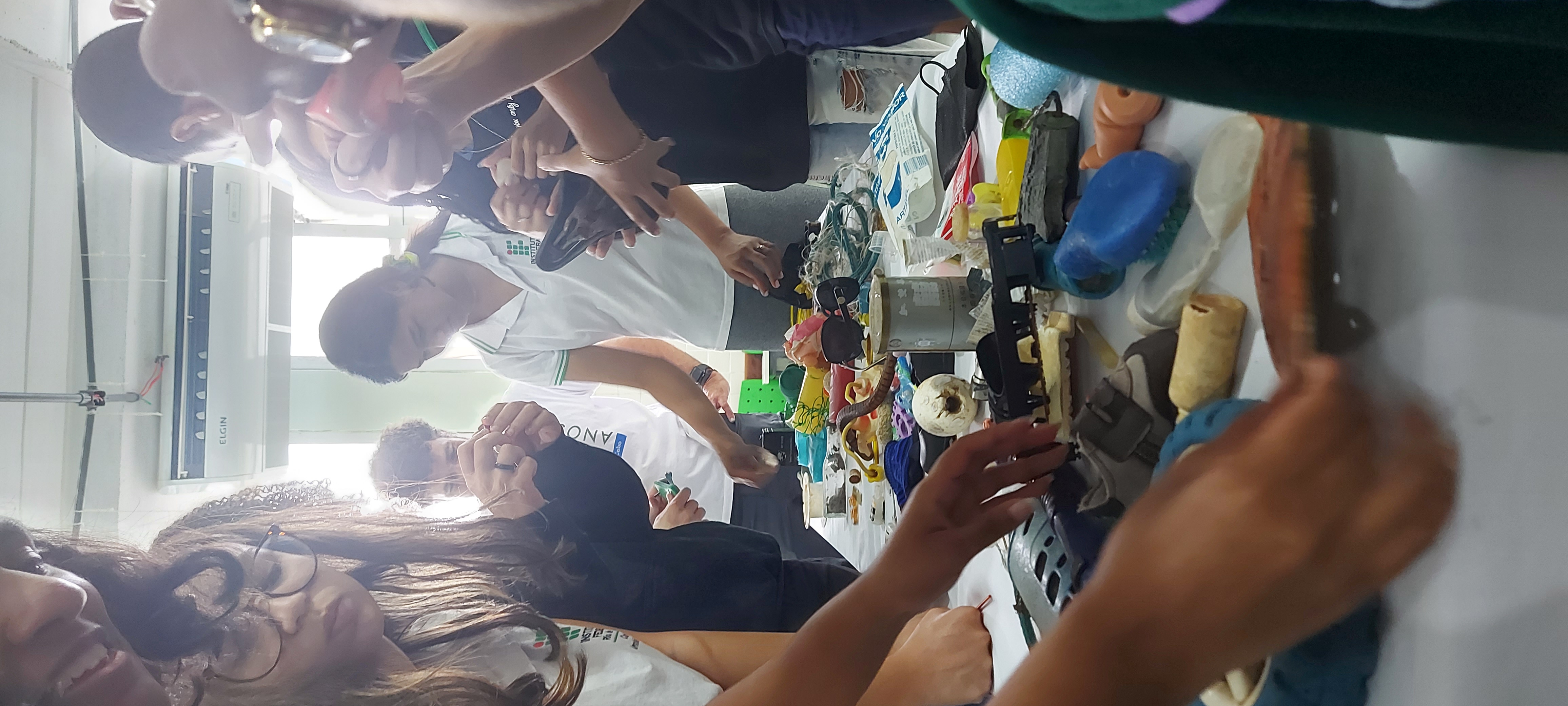 alunos tocam em um pano colorido em cima de uma mesa