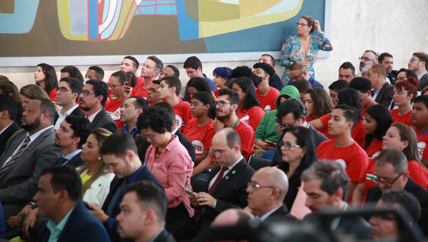 imagem lateral do plenario, com pessoas sentadas e atentas 