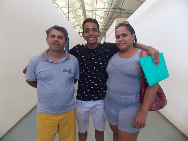 O aluno Marcus Cunha ao centro abraçado com seus pais no dia da inscrição